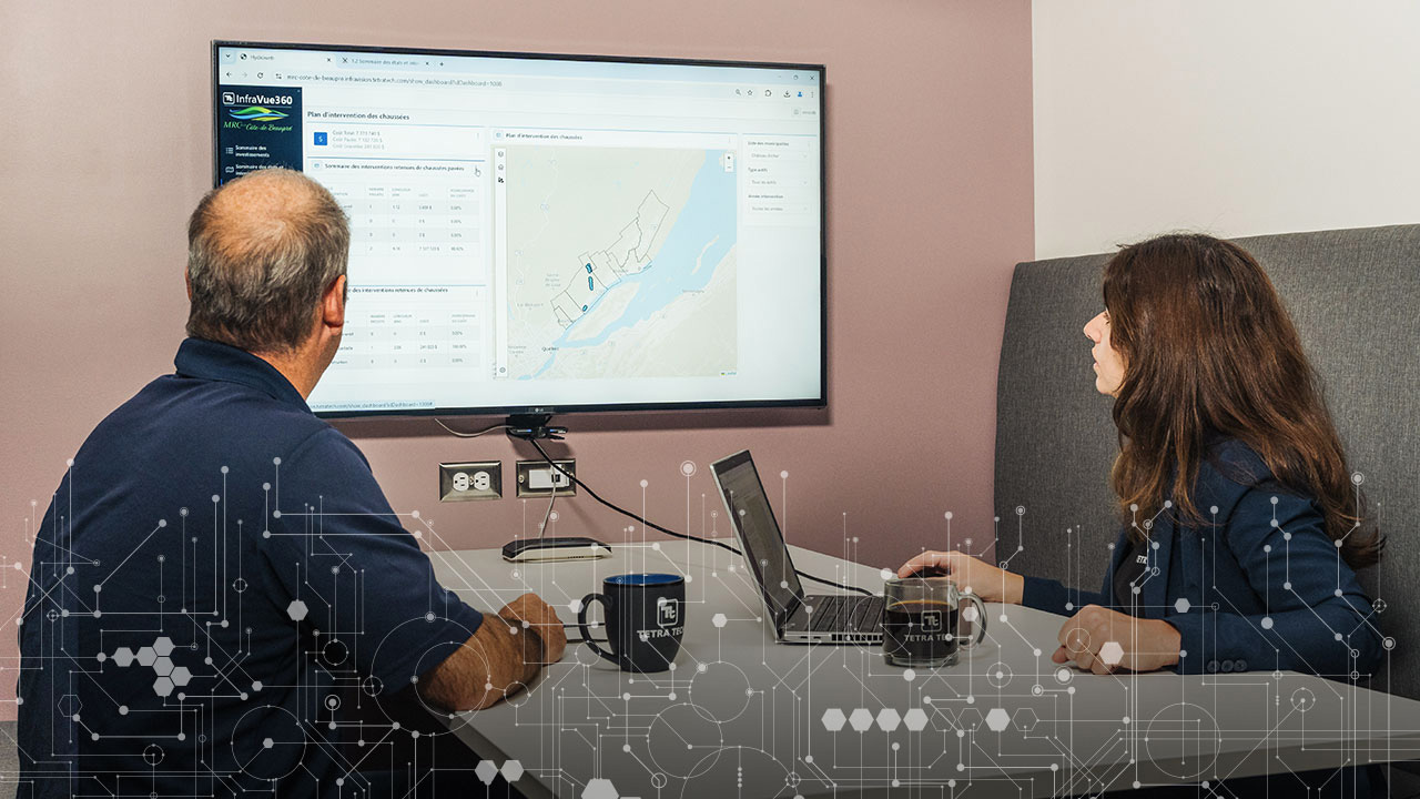 Two people looking at a large monitor displaying Tetra Tech's InfraVue360 platform