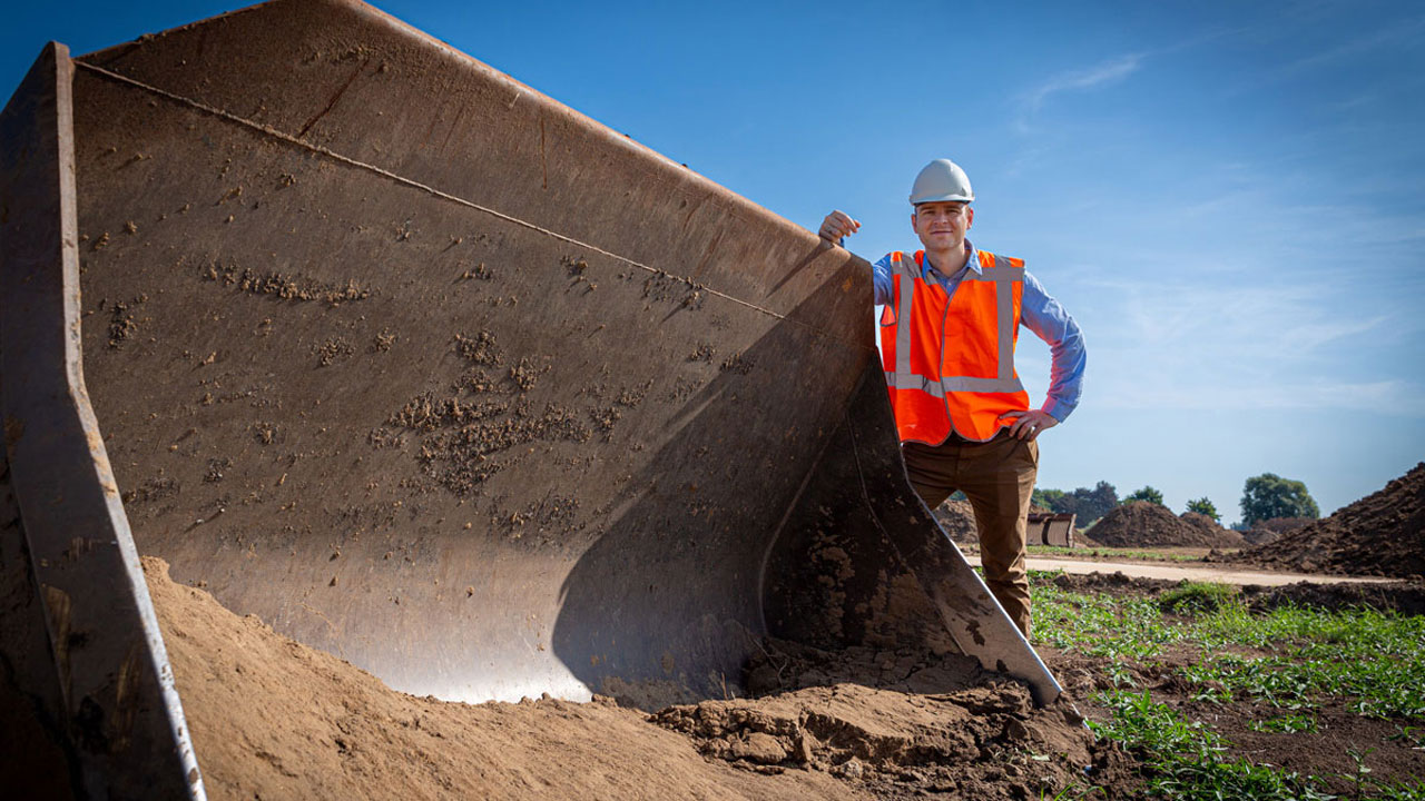 Man in a high visibility vest leans against digger equipment