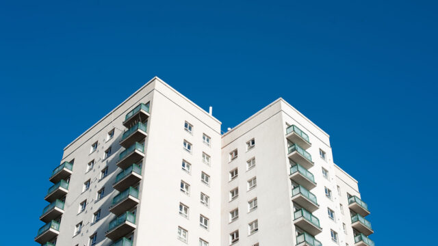 White high rise residential building with blue sky backdrop