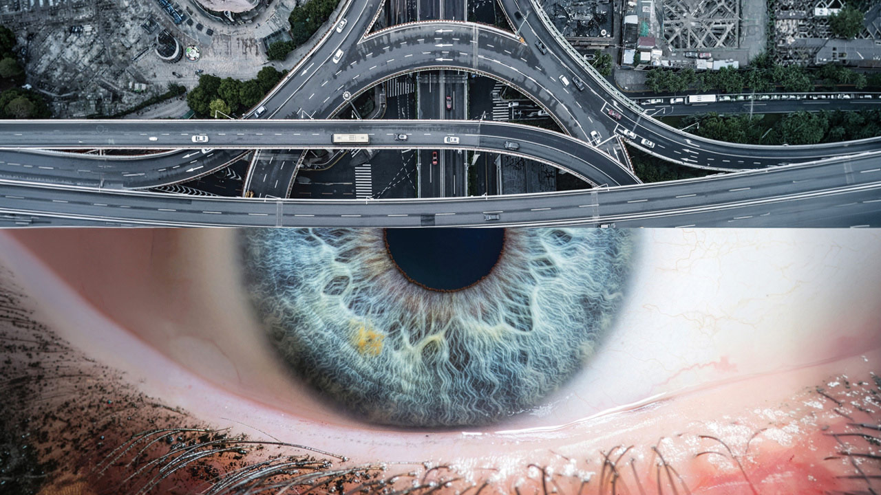 A composite photograph combining an aerial view of a complex highway interchange with a close-up of a human eye