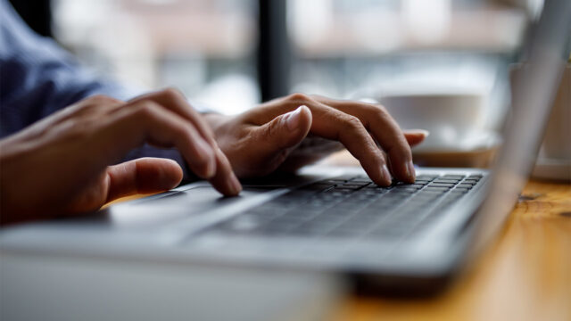 Close up photo of a person's hands typing on a laptop keyboard