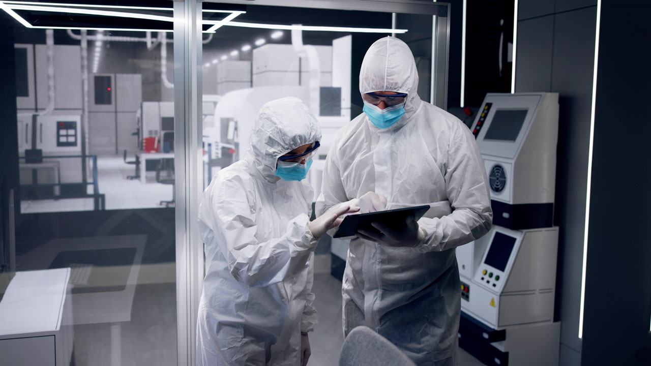 Two people working on a controls tablet in a lab