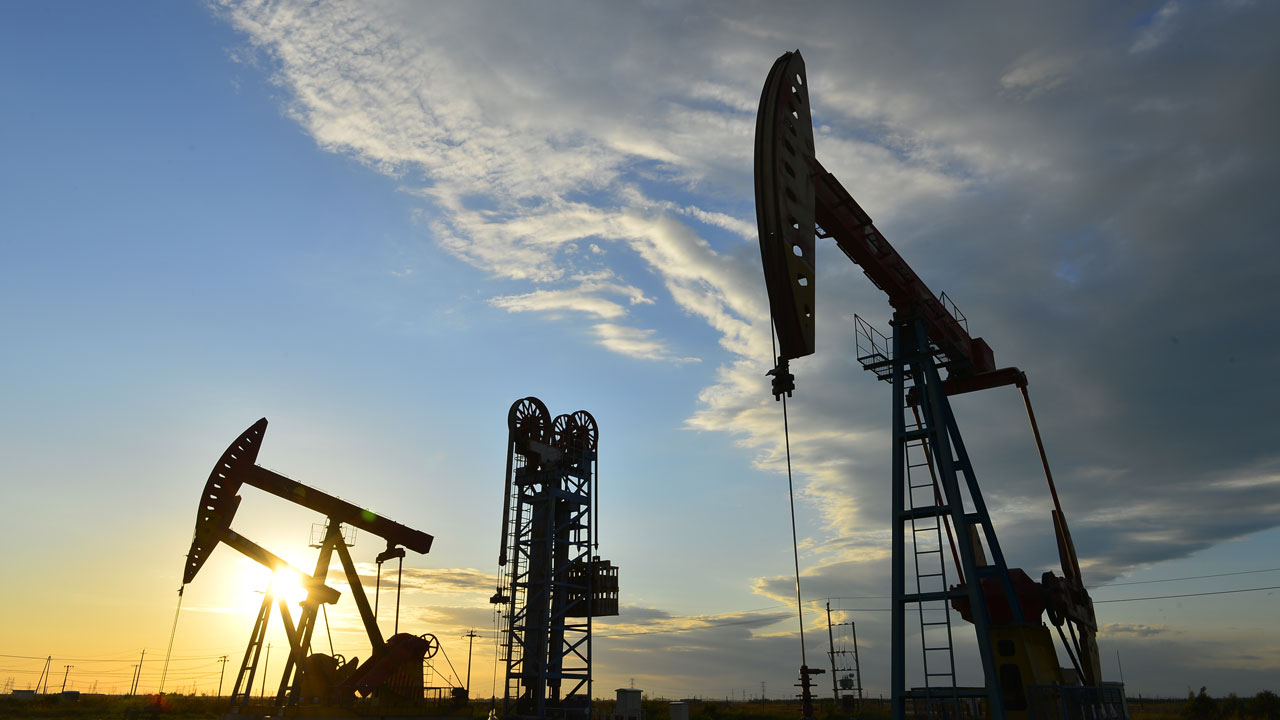 Two oil pumps against a sky at dusk