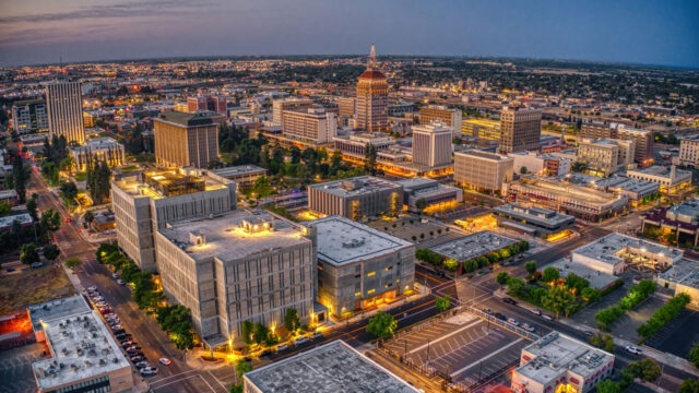 Aerial view of a city skyline at dusk with illuminated buildings and streets
