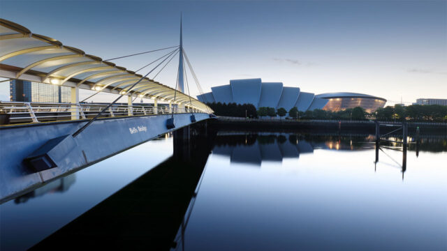 View of the Bells Bridge and Scottish Event Campus building in the background with a body of still water in the foreground