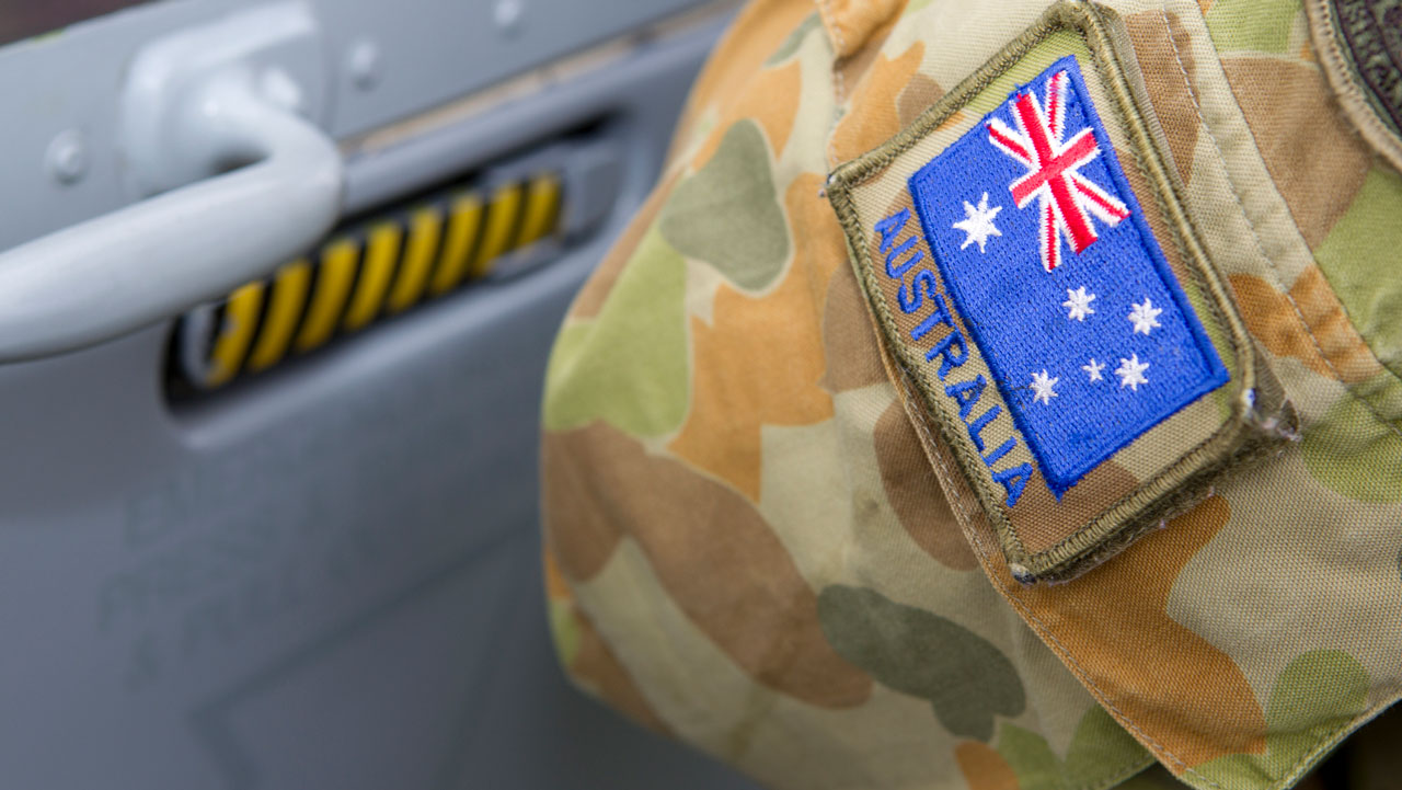 Closeup of an arm in a camouflage uniform with an Australian flag patch attached